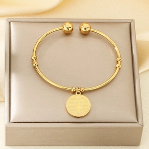 Detailed close-up of 18K gold-plated stainless steel cuff with engraved cross pendant