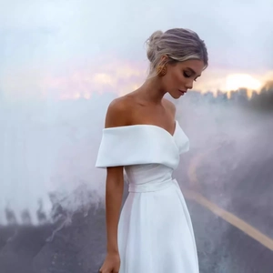 Elegant off-shoulder white satin wedding dress with a cinched waist for bridal photoshoots
