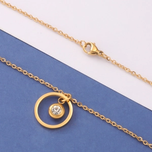 Detail of gold geometric necklace with round clear crystal pendant and lobster clasp