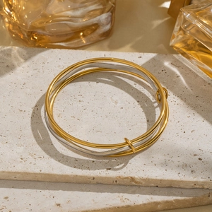 Minimalist gold and silver two-tone geometric layered bangle on a textured stone surface