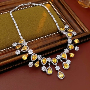 Detailed view of silver Y-shaped necklace with yellow teardrop zircon on a wooden tray