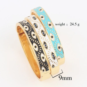 Three stacked gold-plated evil eye bracelets in black, white, and sky blue enamel