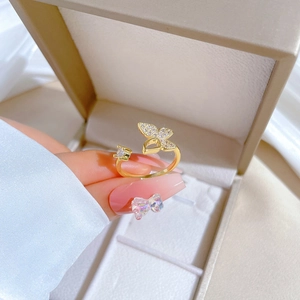 Detailed view of adjustable gold butterfly ring with pavé crystals on finger