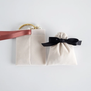 Close-up of cream velvet jewelry pouch with soft texture and elegant black ribbon bow