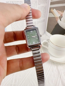 Detail shot of rectangular green dial watch with silver bamboo link band on wrist