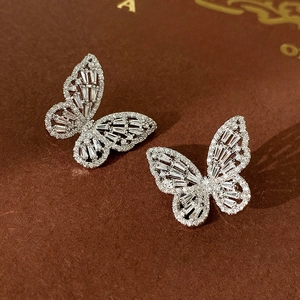 Macro shot of silver butterfly stud earrings with sparkling cubic zirconia on a book