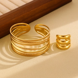Detail view of high-polished gold layered open cuff bracelet and matching triple band ring