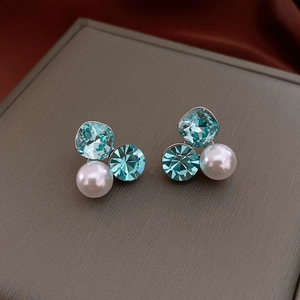 Macro detail of silver needle floral earrings with blue crystals and white pearls