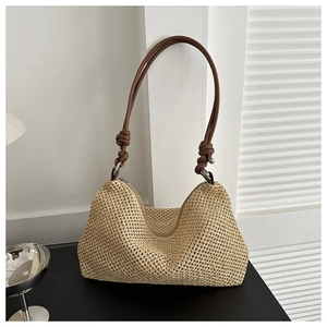 Detail of hand-woven straw shoulder bag featuring stylish knotted leather strap and texture