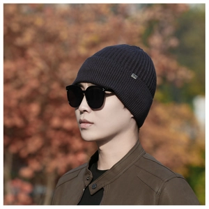 Detailed close-up of navy knit beanie texture with a metal brand tag in a winter setting