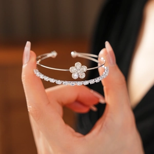 Détail de bracelets joncs doubles argentés avec fleur en zircone et pierres gemmes