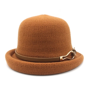Detailed view of the brown knitted cloche hat featuring a leather strap and gold buckle