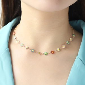 Golden chain necklace featuring colorful enamel daisy flowers on a female model neck