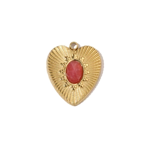 Close-up of heart-shaped gold pendant with red agate stone and sunburst texture