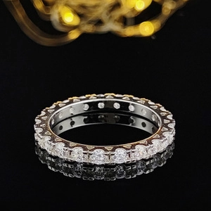 Macro shot of rose gold eternity ring with round cubic zirconia on black mirror background