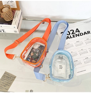 Detail view of colorful transparent PVC crossbody bags with wide straps and gold hardware