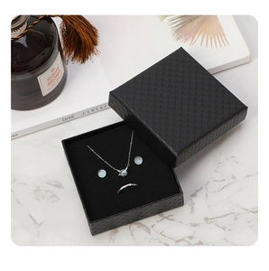 Close-up of a silver jewelry set with planet pendant in a black diamond texture gift box