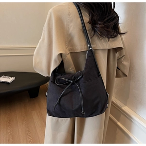 Detail of black drawstring tote bag with decorative bow and suede-like texture