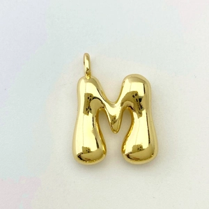 Macro detail of glossy golden balloon bubble letter M pendant with smooth finish