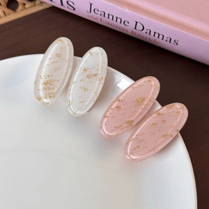 Set of four oval resin hair clips with gold foil in pink and creamy white on a plate