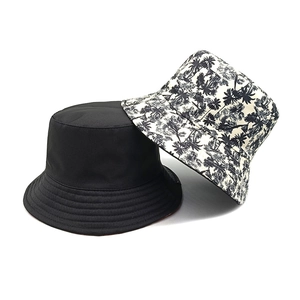 Double-sided bucket hat with coconut tree print and solid black design for beach sun protection