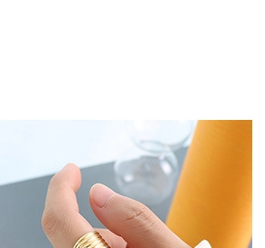 Detail of a textured golden spiral ring with wave patterns on a finger