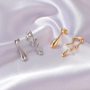 Detail of molten liquid gold and silver irregular earrings on purple silk fabric