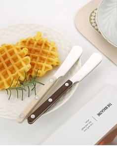 Detail of butter knives with beige and brown handles on a plate with waffles