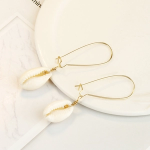 Detail of bohemian natural cowrie shell drop earrings with golden wire-wrapped hooks