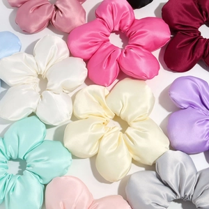 Close-up of assorted colorful satin floral scrunchies with vibrant 3D flower petals