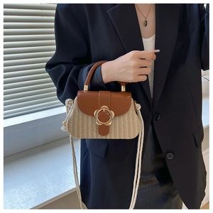 Détail du sac bandoulière en paille tressée avec rabat en cuir et boucle fleurie dorée