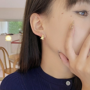 Elegant gold bear earrings made of S925 sterling silver worn by a model in soft light