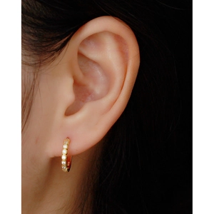 Macro shot of 925 sterling silver hoop earrings with zircon stones on a female ear