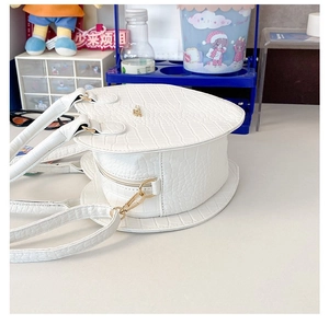 Détail du sac blanc en forme de cœur avec texture crocodile et fermetures éclair dorées