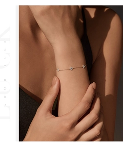 Detailed close-up of a delicate S925 silver four-leaf clover bracelet on woman's wrist