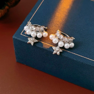 Macro view of silver star earrings with pearls and crystals on blue jewelry box