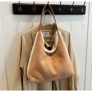 Detail view of brown suede tote bag with white faux fur trim hanging on a coat hook
