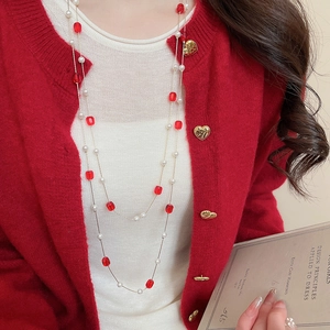 Detail of elegant layered pearl and red crystal bead necklace on a red cardigan