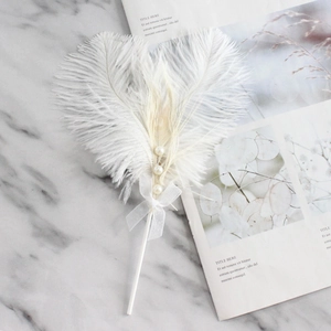 Elegant natural ostrich feathers and pearls cake topper decoration on marble surface