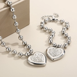 Detail of silver beaded necklace and bracelet set with heart-shaped rhinestone pendant