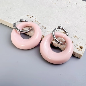 Close-up of pink resin oval hoop earrings with silver stainless steel clasp on stone