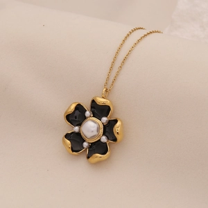 Detailed close-up of a flower pendant with black enamel, gold trim and white pearls