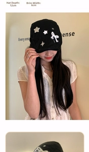 Detail view of black newsboy cap featuring star and bow accents with 12cm depth