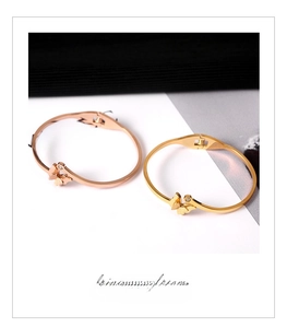 Detail of 18k gold and rose gold butterfly bangles with zircon inlay and matte finish