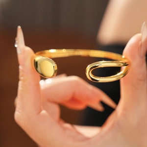 Detailed view of a gold-plated teardrop open bangle with high-polish metallic finish