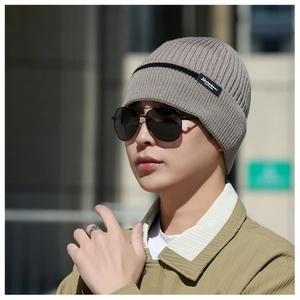 Detail of light brown knitted beanie with fleece lining and fashion brand tag outdoors