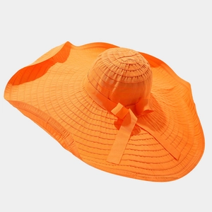Close-up of orange sun hat featuring wide wavy brim and decorative bow detail