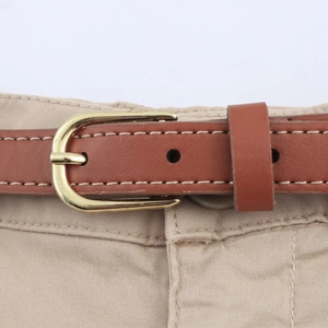 Detail of a thin brown leather belt with a gold metal buckle on beige fabric trousers