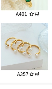 Detail view of 18K gold plated paperclip rings with green emerald and pearls