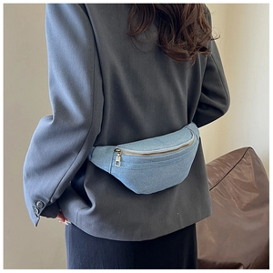 Close-up of light blue denim fanny pack with silver metal zipper on a female model